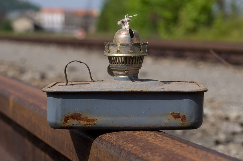 An old kerosene lamp resting on a railway rail